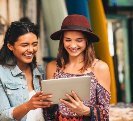 two women holding ipad smiling